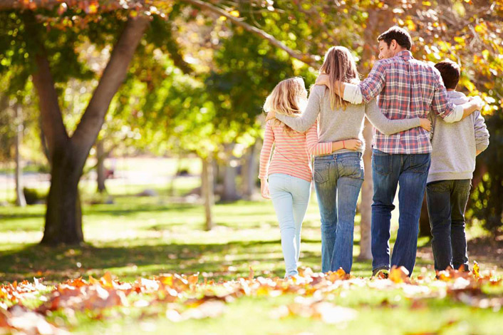 Rear View Of Family Walking Through Autumn Woodland